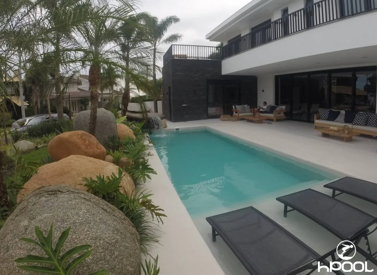 Piscina em L com paisagismo de pedras, executada pela HPool.