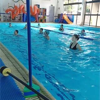 Piscina coberta da academia de natação e hidroginástica, com aula em andamento.